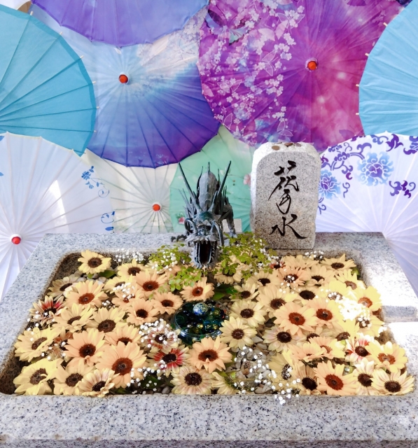 黄色いガーベラが浮かぶ花手水と和傘が並ぶ華やかな装飾
