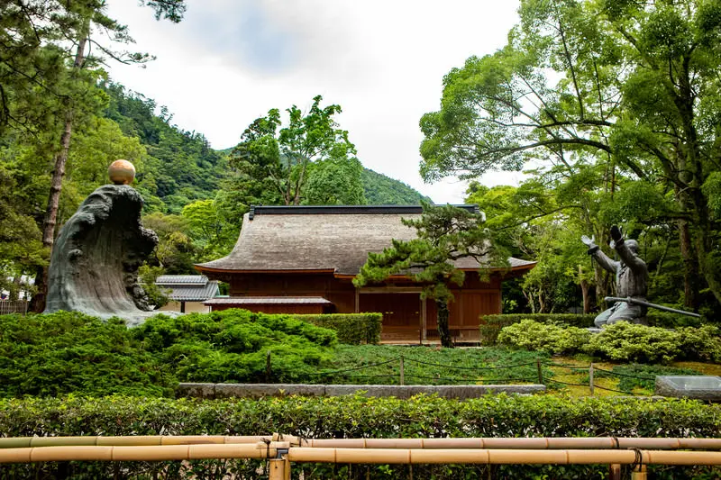 出雲大社の境内にある社殿と、大国主大神と因幡の白兎の像が向かい合う緑豊かな風景