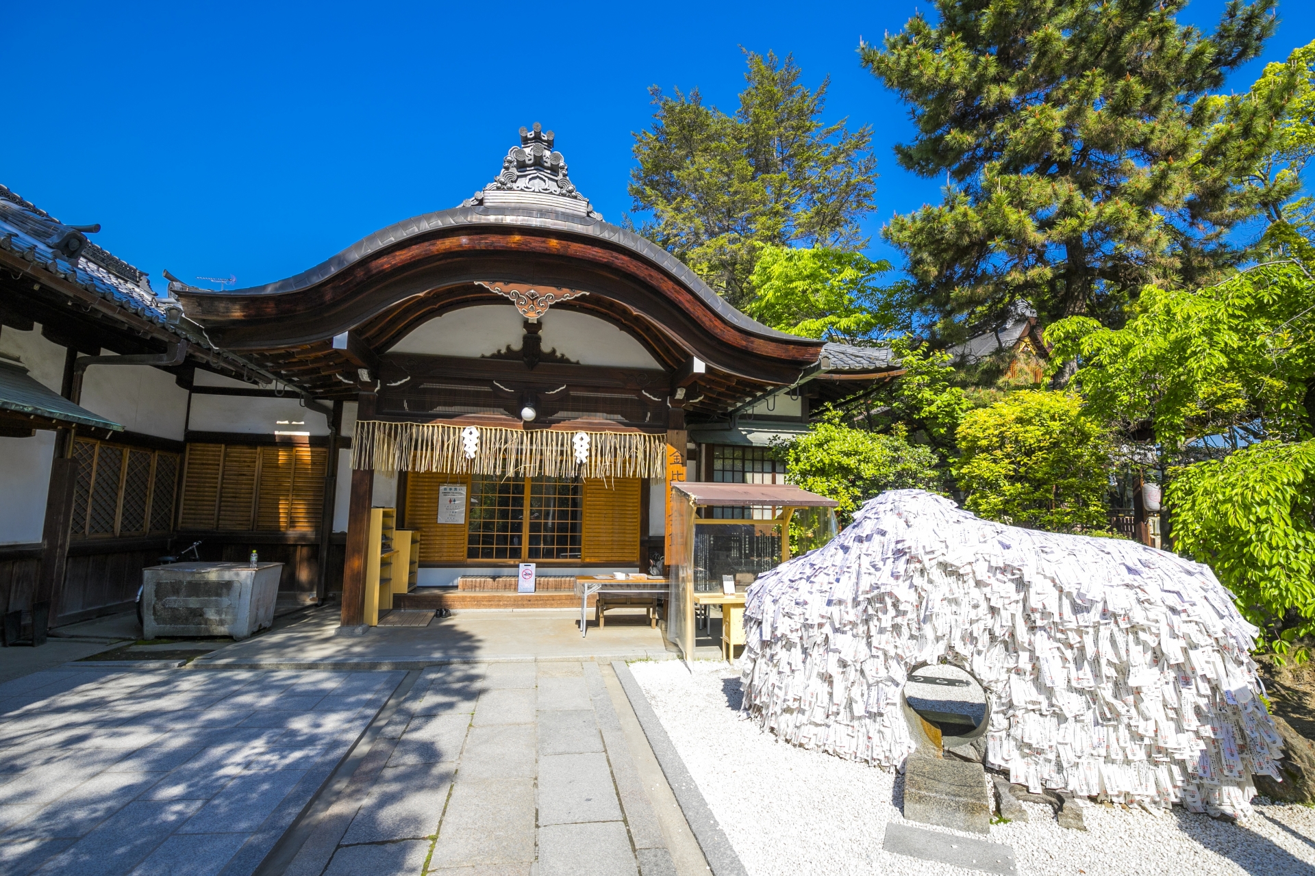 安井金比羅宮の本殿と縁切り縁結び碑の写真。青空と緑に囲まれた神聖な空間。