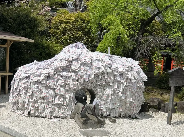 京都 縁結び 神社 安井金比羅宮の「縁切り縁結び碑」。白い形代が無数に貼られた巨石と中央の通り抜け穴。